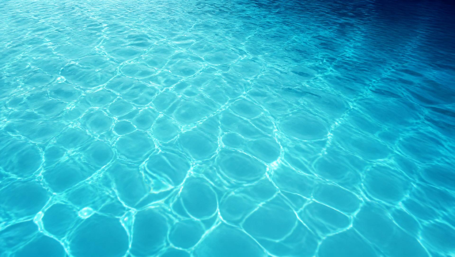 Clean blue swimming pool water with gentle sunlight reflections
